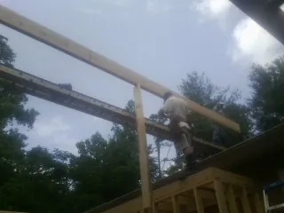 Carpenter setting a ridge beam over a new addition frame — Ice Dam Removal by Roofing Brothers in Penryn