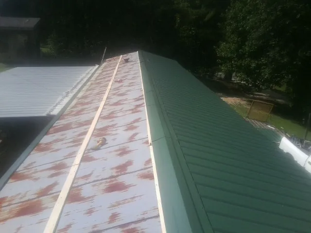 Old rusted panels beside newly installed green metal roofing — Wind Damage Roof Repair by Roofing Brothers in Penryn