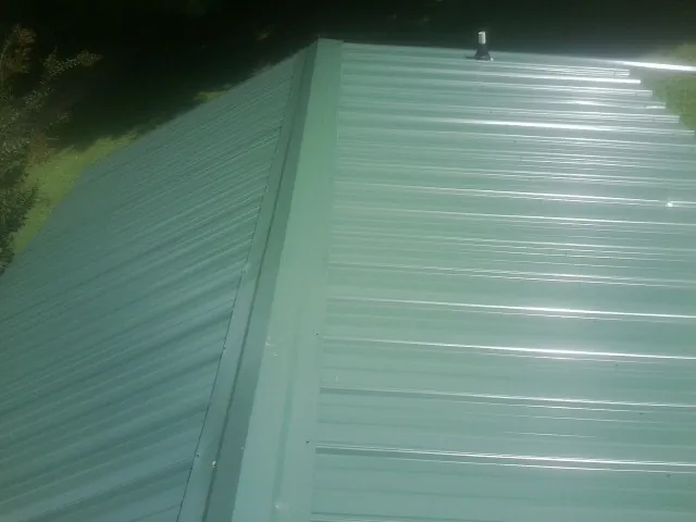 New green metal panels meeting at the ridge of a roof — Flat Roof Repair work by our crew in Penryn