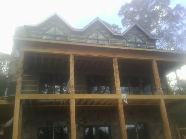 Dormers and porch framing on a large log home under construction — Roof Coating work by our crew in Penryn