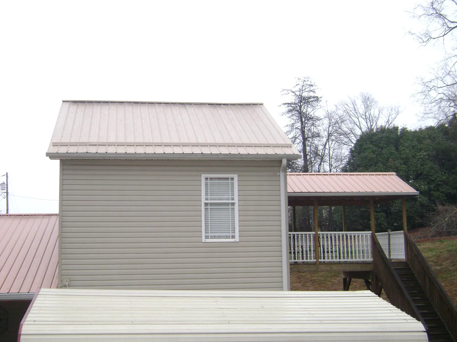 Tan metal roofs on a two story addition and attached porch, from a Roof Replacement job in Penryn